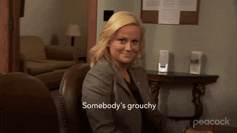 a woman sitting in a chair with the words somebody 's grouchy written below her