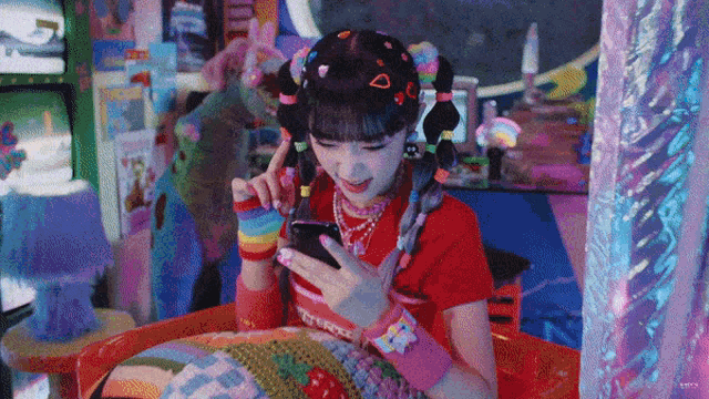 a girl in a red shirt is looking at her cellphone