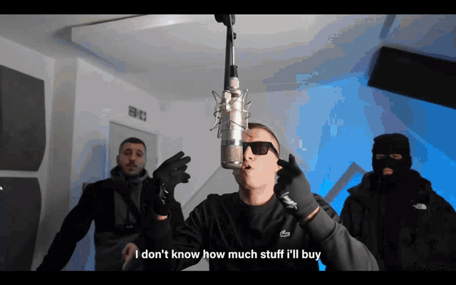 a man singing into a microphone with the words i don t know how much stuff i 'll buy below him