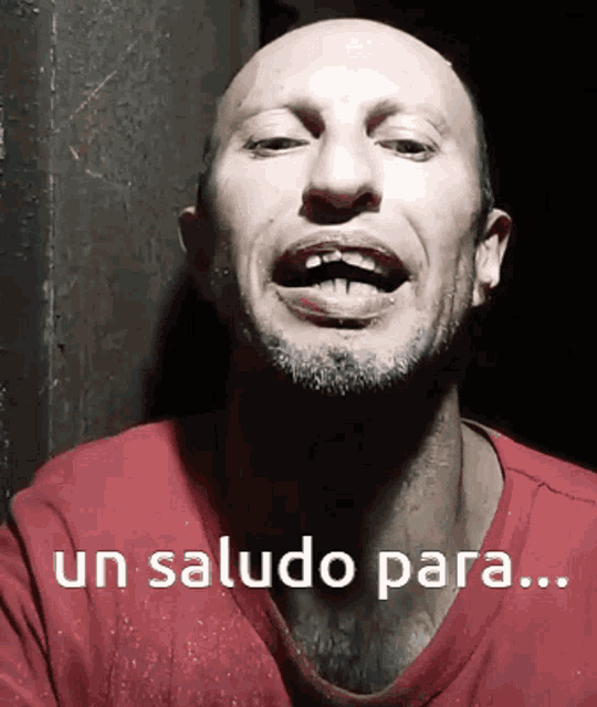 a bald man with a beard is wearing a red shirt that says un saludo para