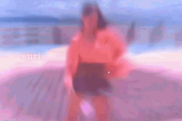a woman in a pink jacket is dancing on a wooden stage with the word surf visible in the background