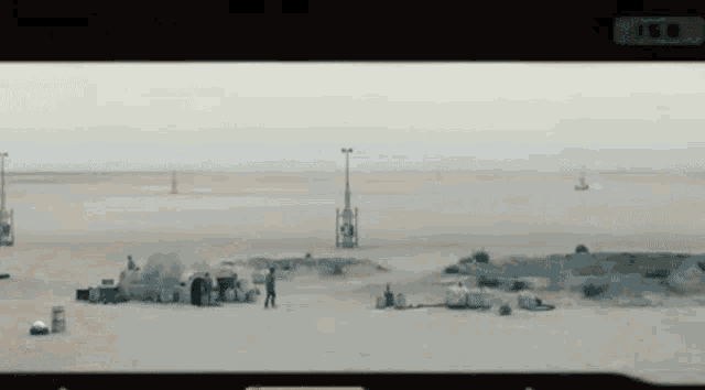 a black and white photo of a desert landscape with a few buildings in the background