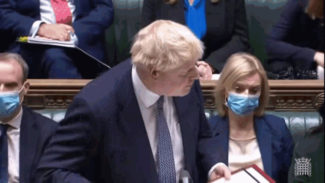 a man in a suit and tie is talking to a woman in a mask