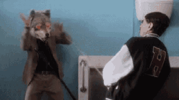a man wearing a wolf mask is standing next to a man wearing a letter h jacket