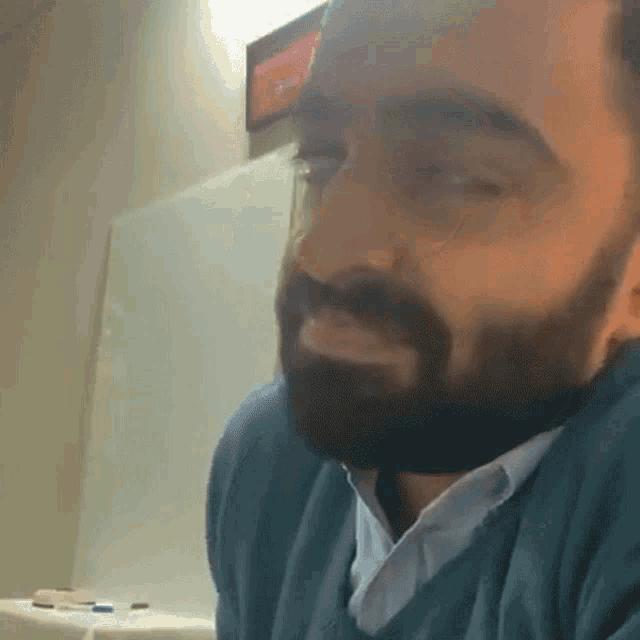 a man with a beard is sitting in front of a white board