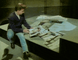 a man is sitting on a table reading a newspaper that says ' a ' on it