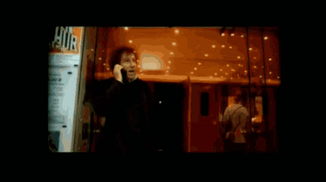 a person talking on a cell phone in front of a sign that says hur