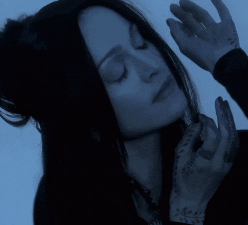 a woman with her eyes closed has a tattoo on her finger