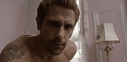 a shirtless man with a tattoo on his arm is standing in front of a lamp .
