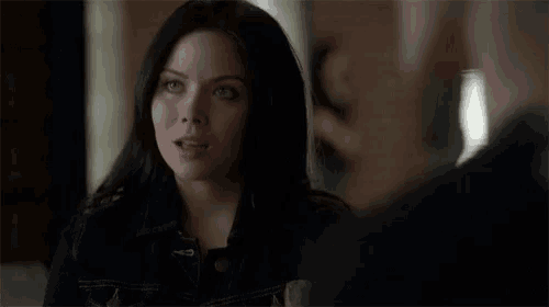 a woman in a denim jacket is talking to a man in a black suit .