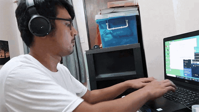a man wearing headphones sits in front of a dell laptop
