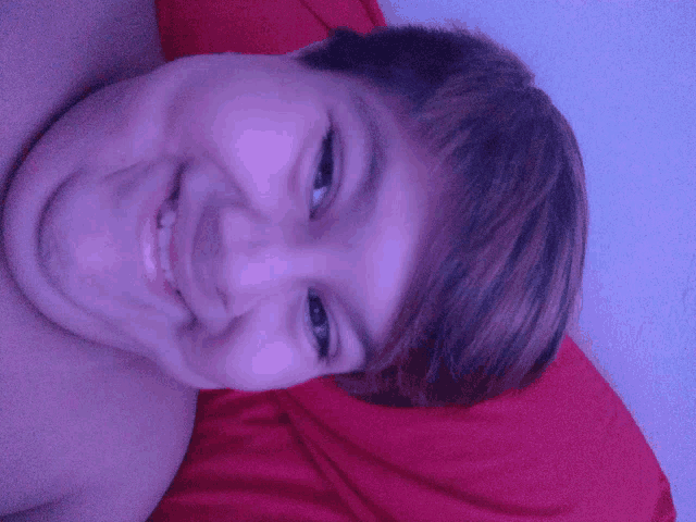 a young boy laying on a bed with a red pillow