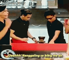 a group of people are standing around a table and one of them is saying " ooohhh! nanggaling sa bibig mo ah "
