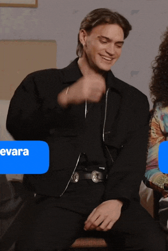 a man in a black jacket is sitting next to a woman with the word evara on a blue bubble