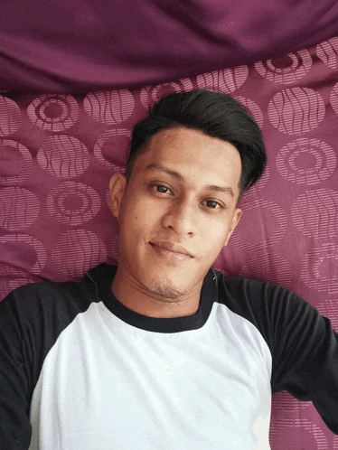 a young man laying on a bed with purple sheets