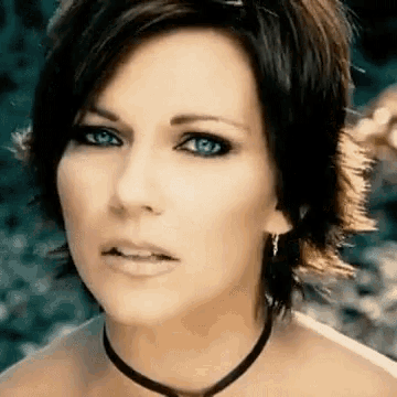 a woman with short hair and blue eyes is wearing a choker necklace .