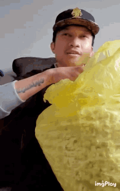 a man in a hat is holding a large yellow bag of popcorn