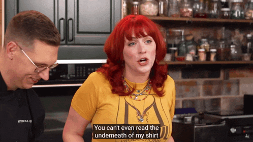 a woman with red hair says you can 't even read the underneath of my shirt in a kitchen