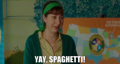 a woman in a green sweater and green headband is smiling and saying yay , spaghetti .
