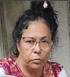 a woman wearing glasses and a bun looks at the camera with a serious look on her face .