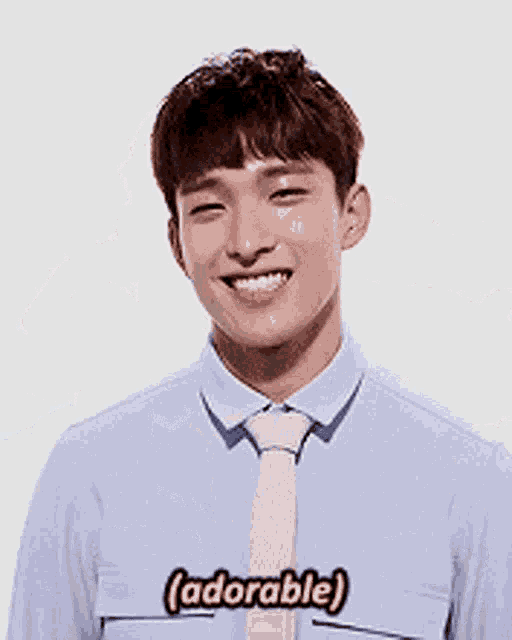 a young man in a blue shirt and pink tie is making a funny face and saying adorable .