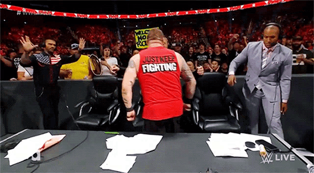 a man in a red shirt that says just keep fighting is standing in front of a crowd