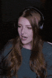a woman wearing headphones and a blue sweater is talking into a microphone