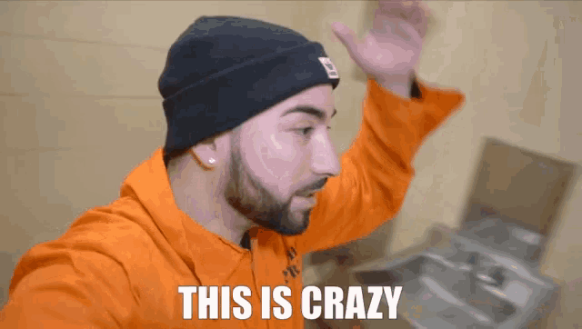 a man with a beard wearing an orange prison uniform says this is crazy