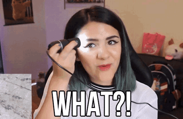 a woman with green hair is holding a flashlight and says " what "