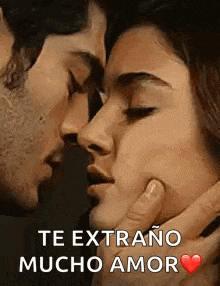 a man and a woman are kissing with the words `` te extrano mucho amor '' written on the bottom .