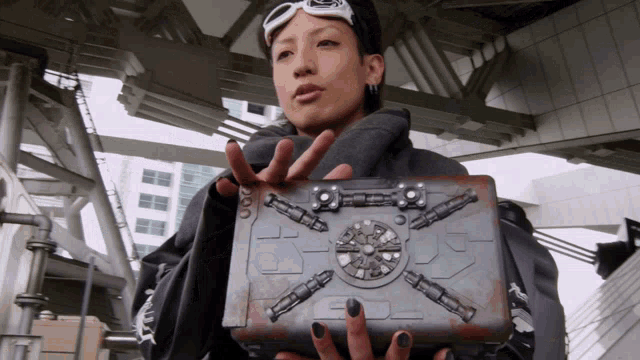 a woman is holding a metal box with a screw on it