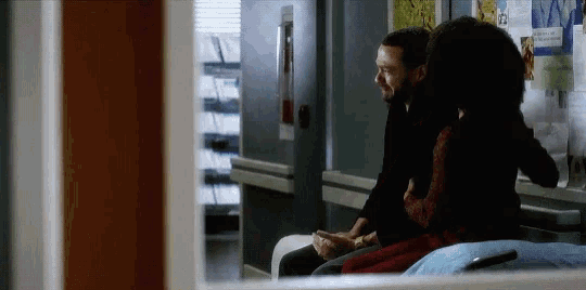 a man and a woman are sitting on a bench in a hospital waiting room