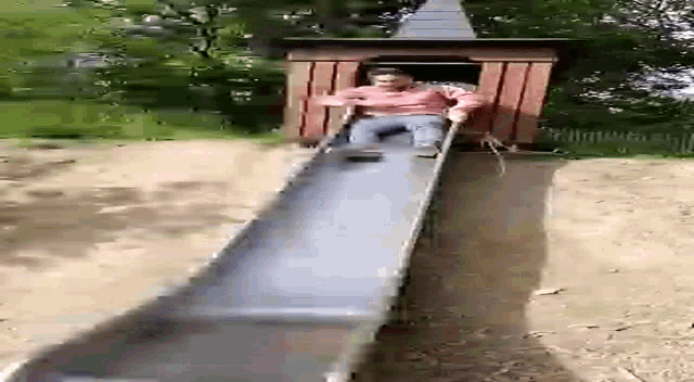 a person is going down a slide at a park