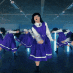 a group of girls in purple dresses are dancing in a dark room