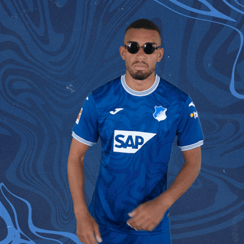 a man wearing sunglasses and a blue shirt with sap on the front