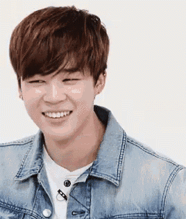 a young man wearing a denim jacket is smiling .