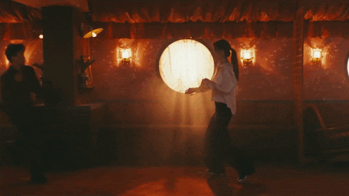 a man and a woman are dancing in a room with a pink wall