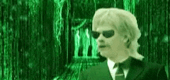 a man wearing sunglasses and a suit is standing in front of a green screen .