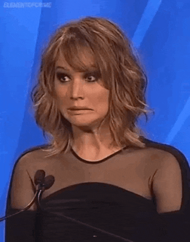 a woman in a black dress is making a funny face while standing at a microphone .