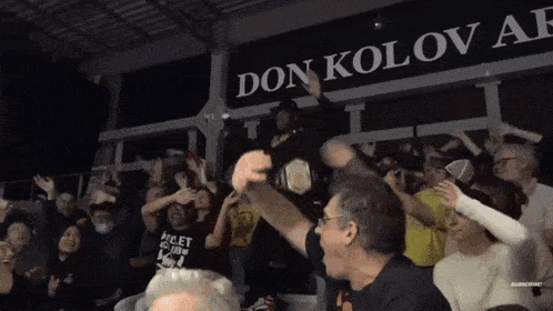 a crowd of people cheering in front of a sign that says don kolov af