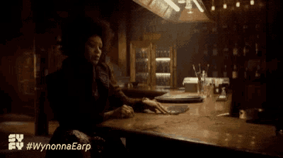 a woman is sitting at a bar with the hashtag #wynonnaearp on the bottom