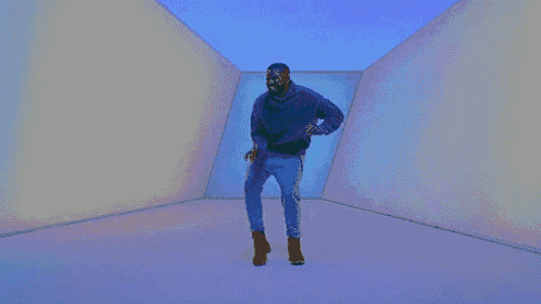 a man is dancing in a room with a blue light behind him .