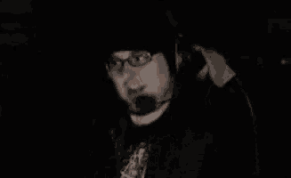 a man with glasses and a hat is wearing headphones and a microphone .