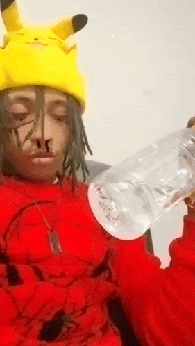 a person wearing a pikachu hat and a red sweater is holding a bottle of water .