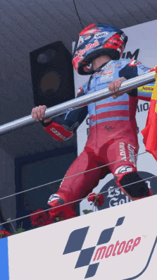 a motorcycle racer stands on a podium with a motogp logo