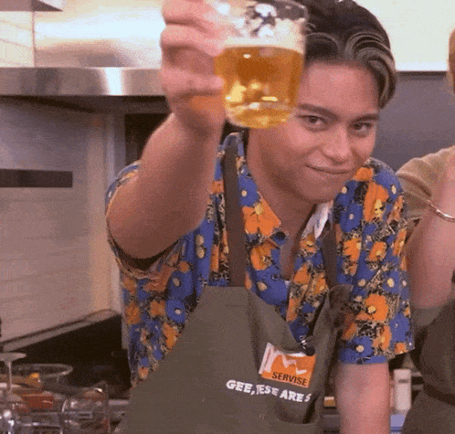 a man wearing an apron that says servise holds a glass of beer