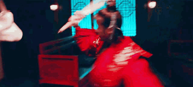 a woman in a red dress is holding a sword and a knife .