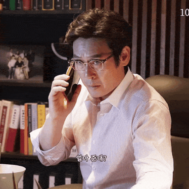a man wearing glasses is talking on a cell phone with the number 10 on the bottom right