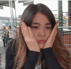 a woman is covering her face with her hands and looking at the camera