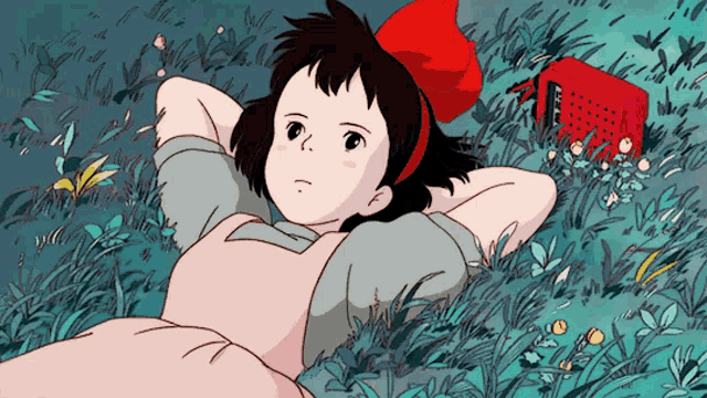 a girl with a red bow laying in the grass